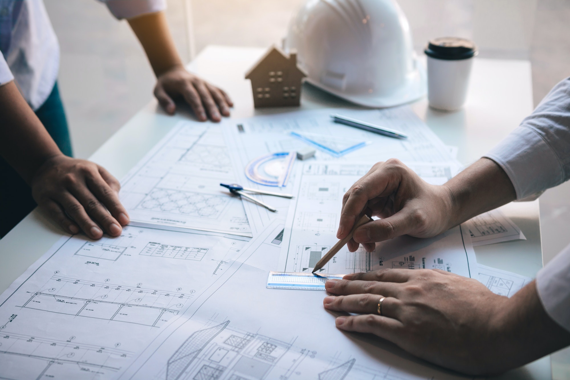 Architect working on blueprint discussing new project with colleague in office.
